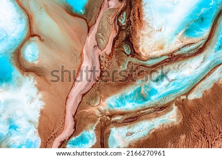 Liquid art texture with pouring colors. Fluid backdrop with flows and cells, waves. Abstract background with splatter inks. Blue, brown and white colors mixing on macro photography picture.