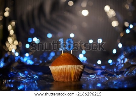 Digital gift card birthday concept. Tasty fresh homemade vanilla cupcake with number 18 eighteen on aluminium foil and blurred bright background in minimalistic style. High quality image