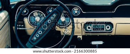 Retro styled image of an old classic sports car dashboard with black and white interiors. Royalty-Free Stock Photo #2166300885