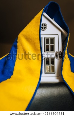 Ukrainian house, city with national yellow-blue flag. Shelter for homeless refugees from Ukraine to Europe affected by the war. Conflict concept, photography.