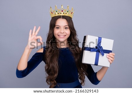 Child with gift present box on isolated studio background. Gifting for kids birthday. Happy face, positive and smiling emotions of teenager girl.