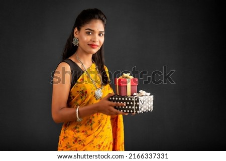 Portrait of young happy smiling woman Girl holding gift box on a grey background.