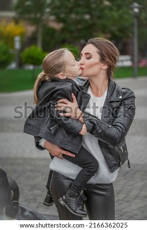 Mom carries her daughter in her arms while walking in the city