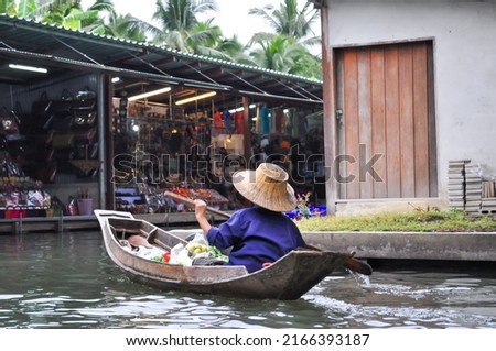 Thailand, Pattaya, december 24, 2021: Tourists on boats sail past wooden houses built on the riverbank, take pictures of the life of local residents. Blurry, defocused, selective focus
