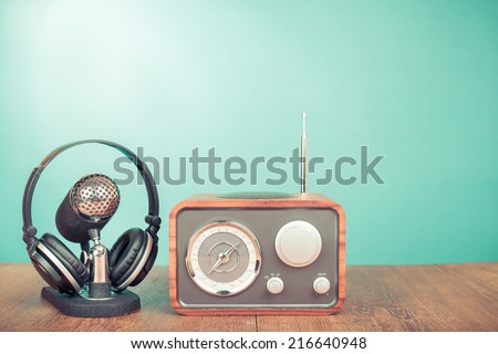 Retro wooden radio, old microphone and headphones front mint green wall background