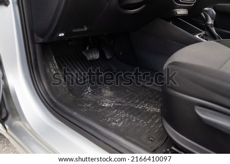 Dirty car floor mats of black rubber with gas pedals and brakes in the workshop for the detailing vehicle before dry cleaning. Auto service industry. Interior of sedan. Royalty-Free Stock Photo #2166410097