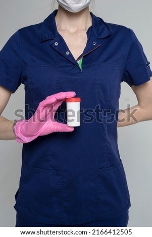 a girl doctor holds a package of pills in front of her on a white background in medical clothes
