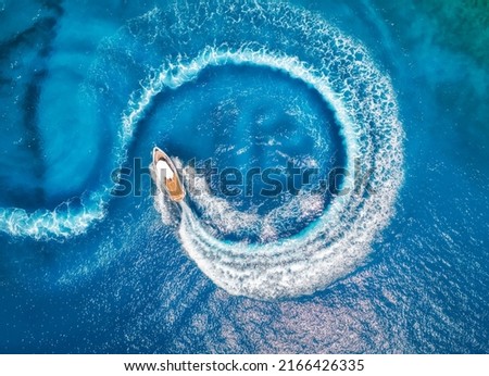 Aerial view of the speed boat in clear blue water at sunset in summer. Top view from drone of fast floating yacht in mediterranean sea. Travel in Oludeniz, Turkey. Tropical landscape with motorboat Royalty-Free Stock Photo #2166426335