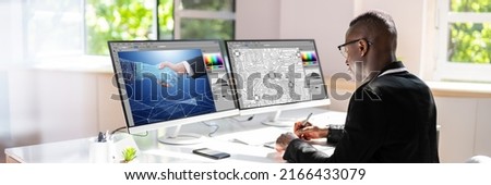 Young Male Designer Editing Photos On Computer In Office