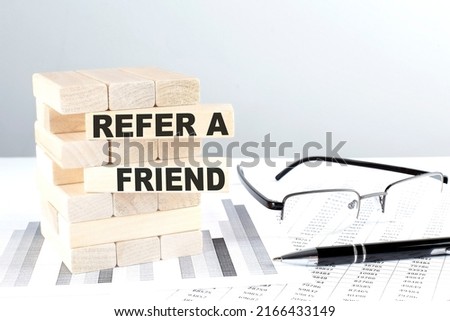 REFER A FRIEND is written on a wooden blocks on a chart background