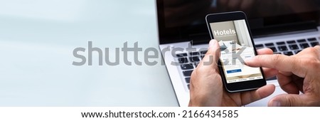 Close-up Of A Man's Hand Booking Hotel Using Smartphone Royalty-Free Stock Photo #2166434585