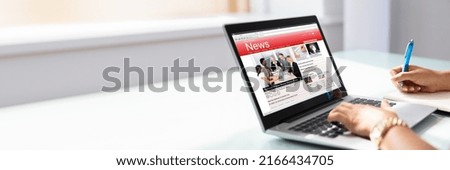 Close-up Of Businesswoman's Hand Checking Online News On Laptop In Office