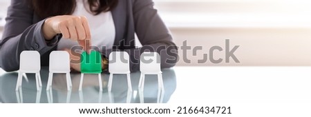 Close-up Of A Businesswoman's Hand Choosing Green Chair Among White Chairs In A Row Royalty-Free Stock Photo #2166434721