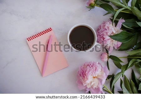 Cup of coffee, peony flower, notebook on a light background
