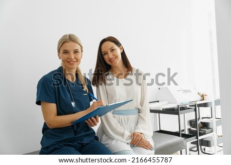 Smiling doctor fills out the medical report form on medical care of patients during appointment 