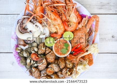 seafood plate with shrimp shellfish crab squid cockle spotted babylon with seafood sauce chili lemon lime serve on dining table, shrimps prawns seafood buffet menu cooked food Royalty-Free Stock Photo #2166473123