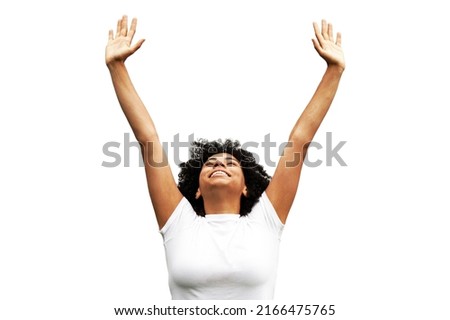 Young attractive African American woman stands wearing a white shirt against an isolated white background with her arms up celebrating                                Royalty-Free Stock Photo #2166475765