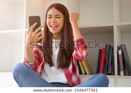 Happy teens Asian female college student receiving an unexpected email or good news from her university via smart mobile phone.