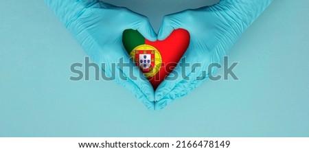Doctors hands wearing blue surgical gloves making hear shape symbol with portugal flag