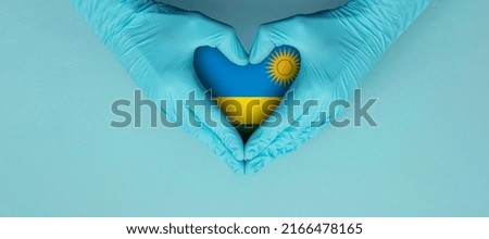 Doctors hands wearing blue surgical gloves making hear shape symbol with rwanda flag