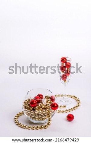 New Year's still life: vase and glass with red Christmas tree toys on a white background with a place for text