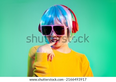 Young asian woman in yellow sweatshirt short and blue color hair punk style wearing fashion sunglasses and headphone posing on the green screen background. 