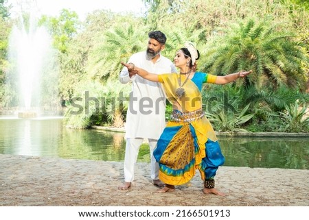 Indian woman learning Odissi classical dance form, male teacher or coach teaching female dancer and correcting pose, Orissi dance, art and culture of india. Royalty-Free Stock Photo #2166501913