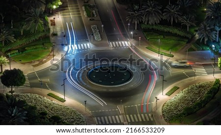 Traffic on a road intersection with roundabout in Greens district aerial night timelapse. Dubai skyline with many cars on a crossroad with fountain Royalty-Free Stock Photo #2166533209