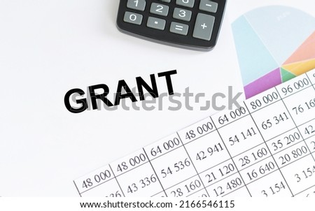 GRANT text on a notepad on the table among reports and a calculator, a business concept