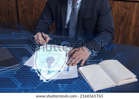 A businessman in formal wear signing the contract to prevent probability of risks in cyber security. Padlock Hologram icons over the working desk.