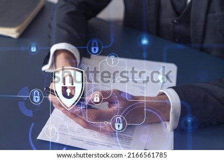 A businessman in formal wear reading the contract to prevent probability of risks in cyber security and checking details in the phone. Padlock Hologram icons over the working desk. Royalty-Free Stock Photo #2166561785