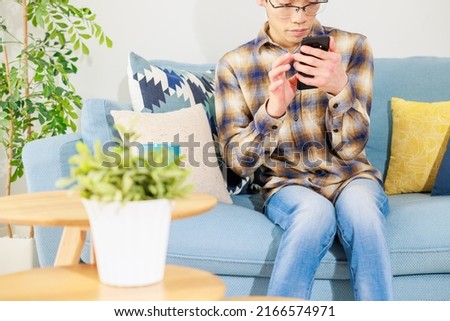 A man sitting on the sofa and looking at a mobile phone