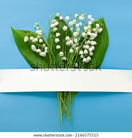 greeting card with lily of the valley flowers on a blue background, flat lay for design, top view, place for text, floral spring background