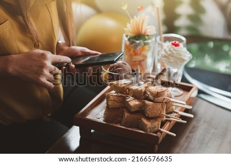 Woman preparing to photograph cakes and drinks, Piccolo Latte, brownies and breakfast on wooden table with smartphone.