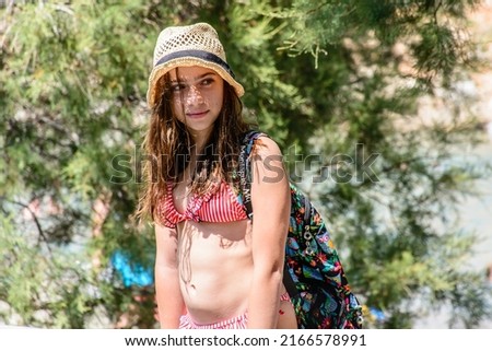 girl wearing hat and swimsuit walking on the beach
