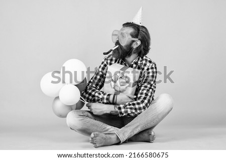 anniversary. have a happy holiday. party time. happy birthday to you. bearded mature man celebrate birthday party. cheerful man in bday hat hold holiday balloons. gifts and presents concept