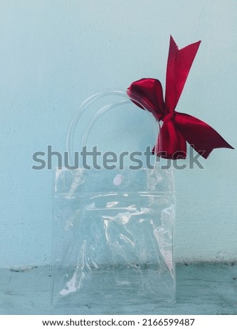 Plain plastic bag with handle and red ribbon decoration