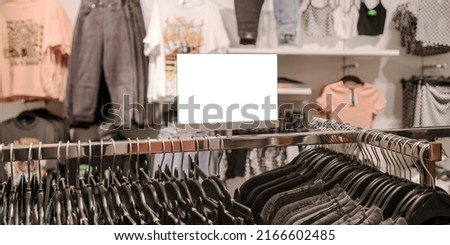 Blank white price tag stands on metal rack in city mall clothes department. Sale and discount concept.