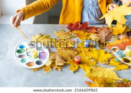 mother and daughter paint autumn leaves