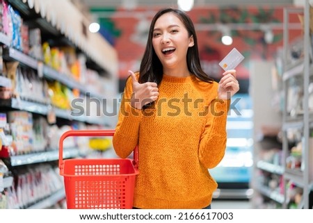 happiness shopping with credit card asian cheerful female smiling hand show cardit card cashless payment  hold empty basket ready to choose consumer product with joyful in supermarket business concept