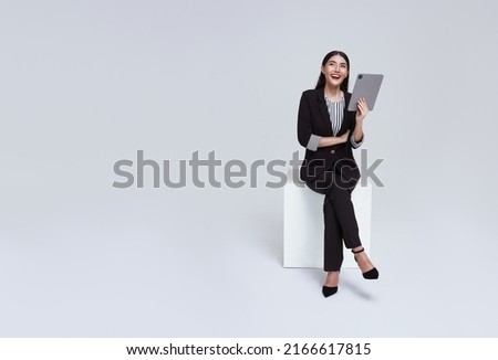 friendly face asian businesswoman smile in formal suit sitting on chair her using tablet and looking to copyspace isolated on white background studio shot. Royalty-Free Stock Photo #2166617815