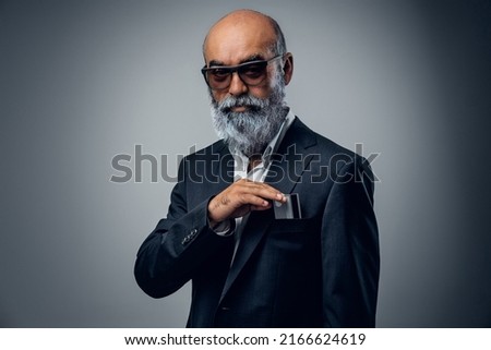 Shot of senior businessman dressed in stylish suit and sunglasses with bank card.