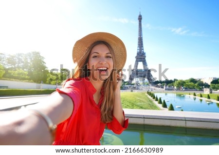 Fashion tourist woman with red dress and hat makes selfie photo with Eiffel Tower on the background in Paris, France. Concept travel. Royalty-Free Stock Photo #2166630989