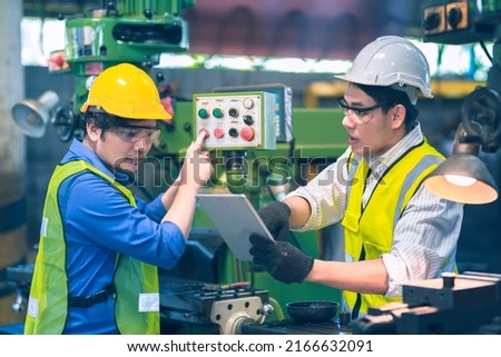 The worker teammate engineer white and yellow safety helmet during working together with tablet follow instruction with machine in the factory industrial