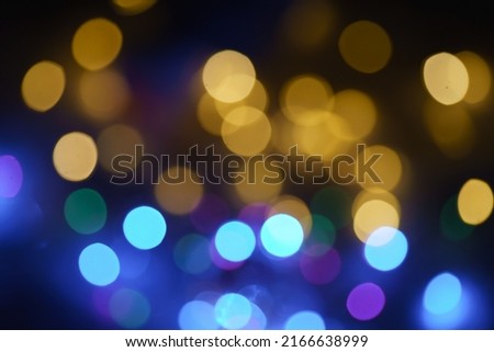 Photography of New Year lights in night. Christmas mood, festive atmosphere. Suitable as template and background for postcards, greeting cards. Blue, purple, violetб golden and black colors