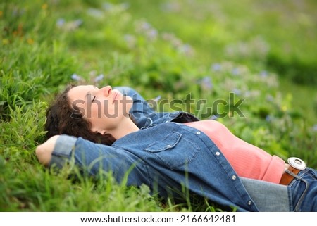 Beautiful woman resting and relaxing lying on the grass in a park Royalty-Free Stock Photo #2166642481