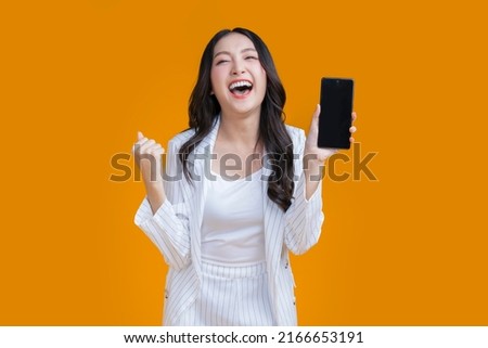 exited surprise face expression asian business woman female hand gesture exited with successful progress result on smartphone screen display  exited raised hands up isolated on bright yellow color Royalty-Free Stock Photo #2166653191