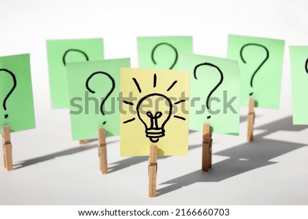 A lot of clothespins with question marks on stickers and on one light bulb, as a sign of a good idea. Concept of business, management, markets, creativity.