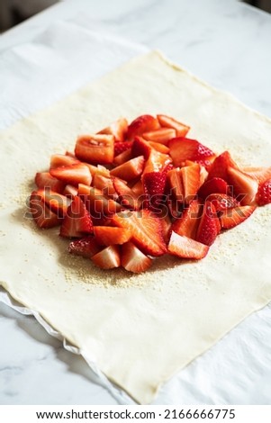Summer strawberry galette with almond flakes in making. Food preparation concept.