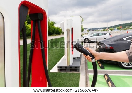 Man holding plug of electric car charging station  Royalty-Free Stock Photo #2166676449